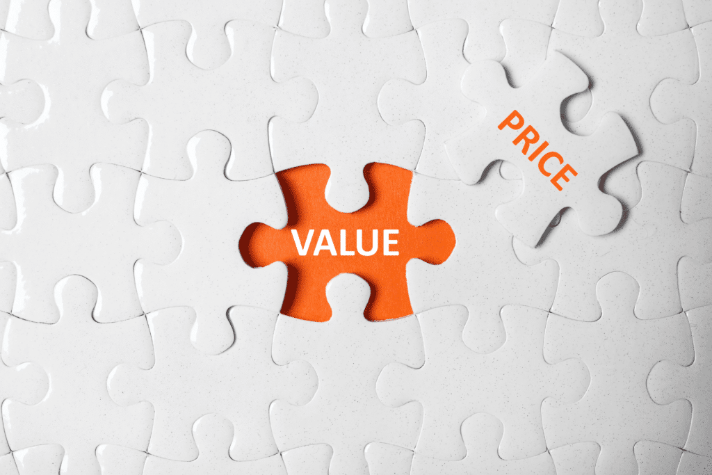 A white puzzle with one piece missing reveals an orange piece labeled VALUE, perfectly encapsulating Affordable Managed IT Services: Enhancing Business Efficiency. Nearby, a separate puzzle piece is labeled PRICE, symbolizing the harmony between cost and service excellence.