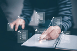 A person is using a laptop and writing in a notebook. Overlay graphics of digital documents with checkmarks and signatures float above, suggesting online document management or MSP contracts for efficient task completion.