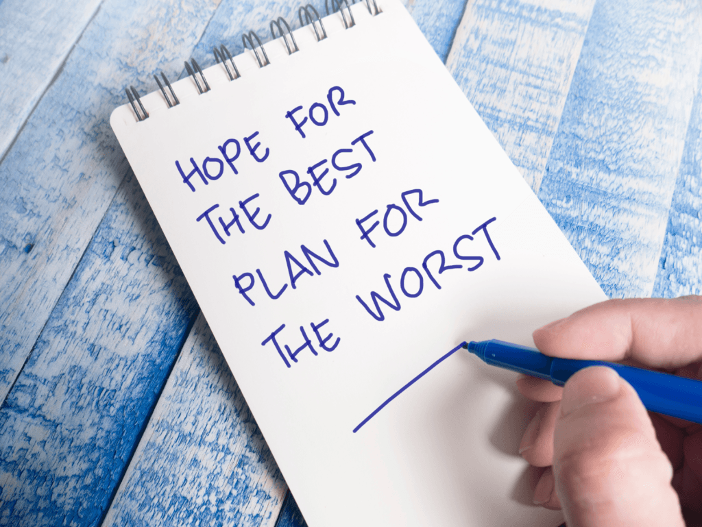 A hand writes with a blue pen on a notepad, displaying the phrase "Hope for the best, plan for the worst" against a blue and white wooden background—a gentle reminder of how HIPAA-compliant IT services ensure data security and compliance.